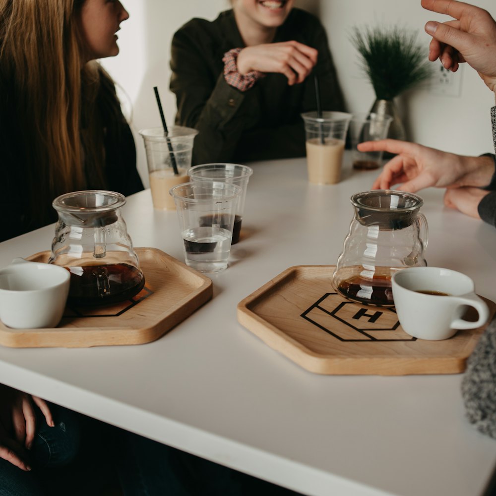 Friends talking around a table set with brew carafes on wooden trays