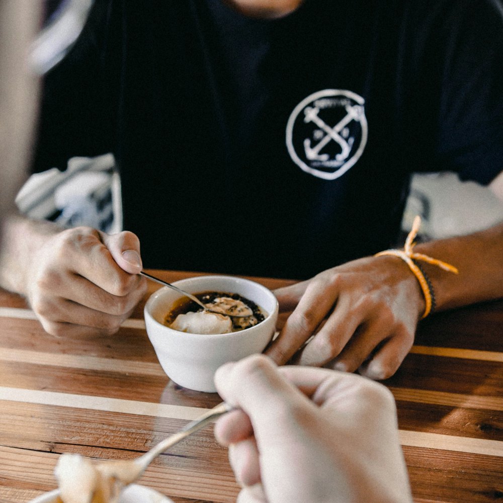 Hands cradling a small cup of coffee at a dark table