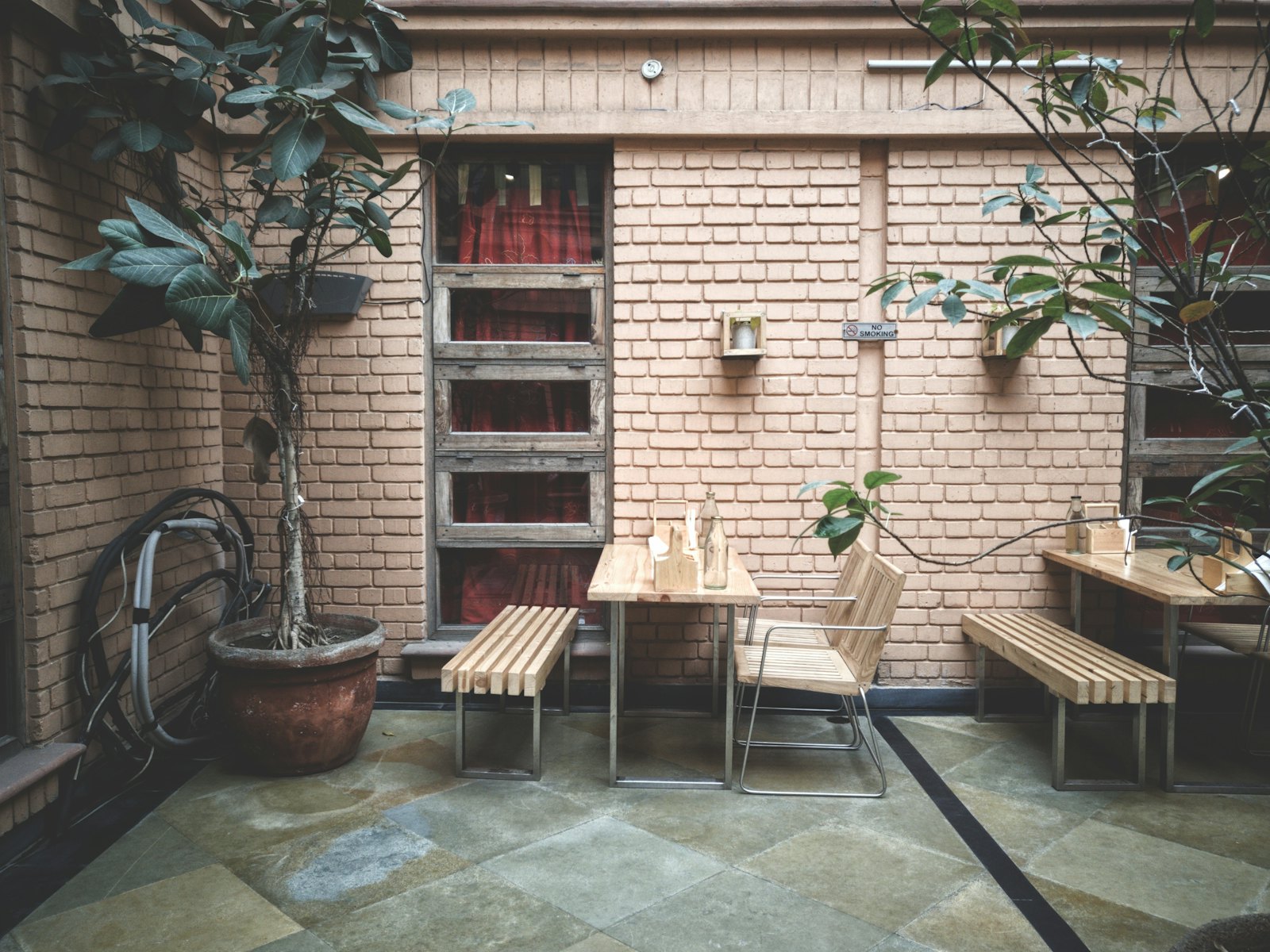 A small café table and chair against an exposed brick wall with a trailing plant