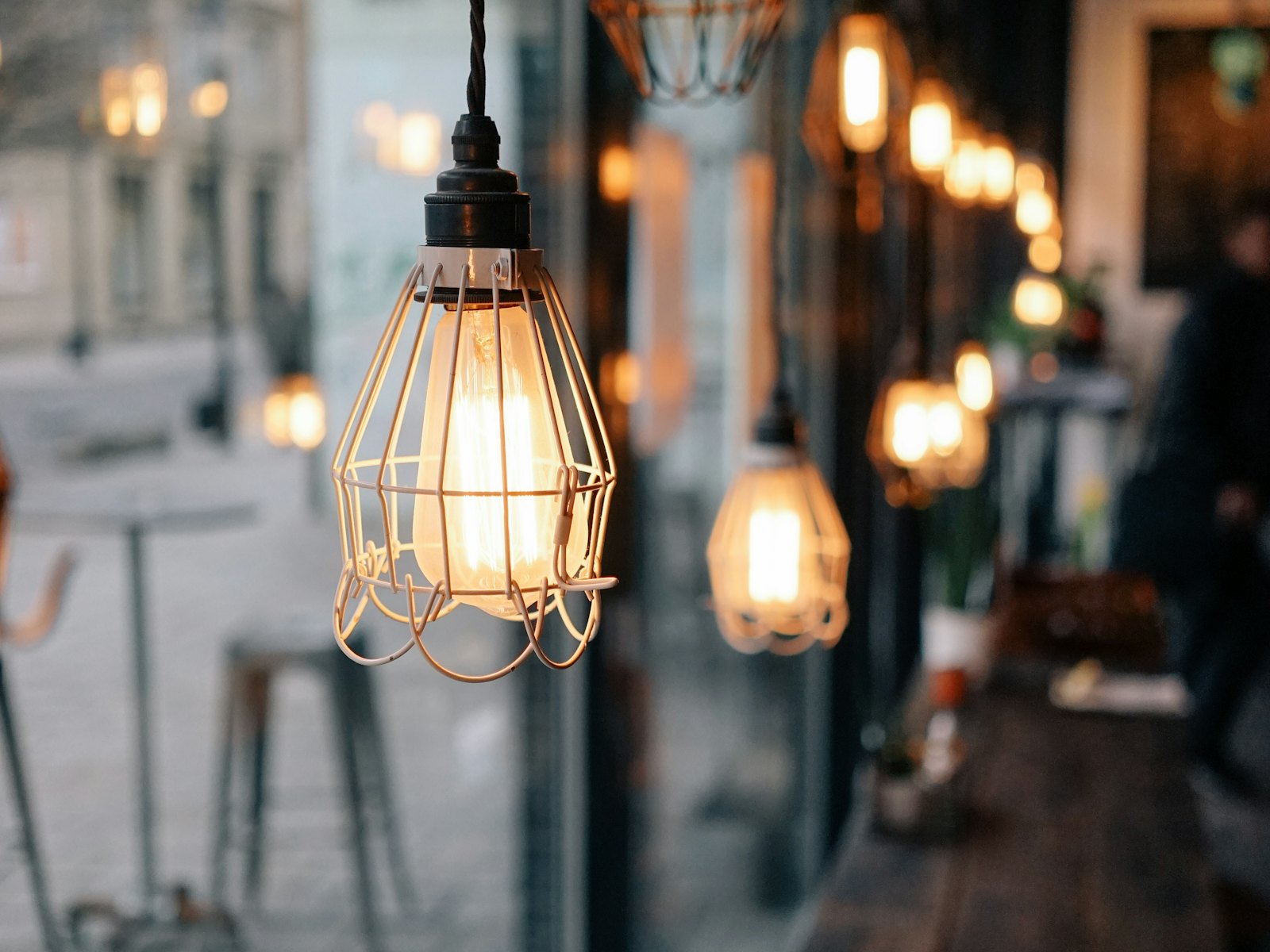 A row of brass pendant lamps glowing above the café counter