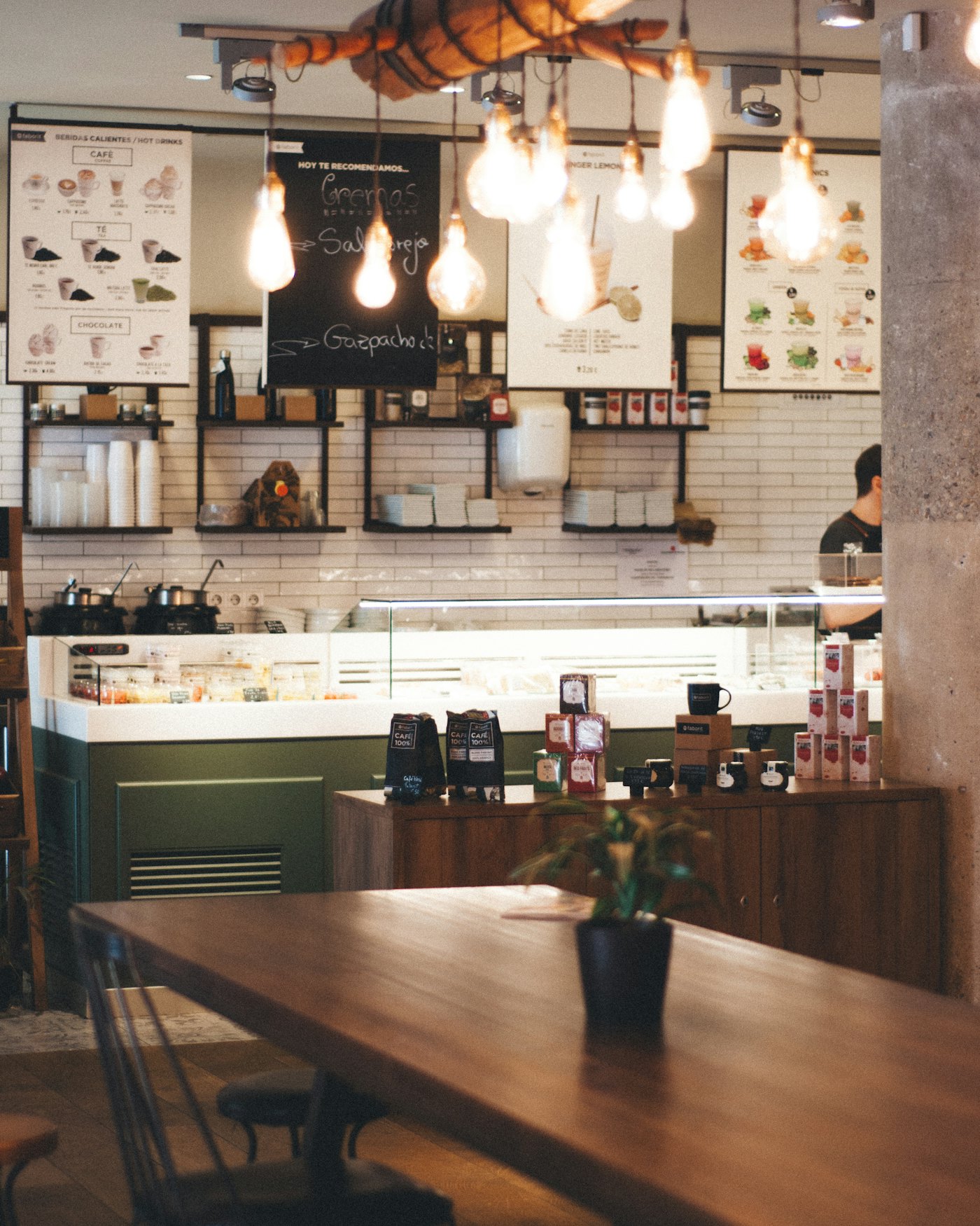 Café interior at golden hour with pendant bulbs hanging over a shared timber table