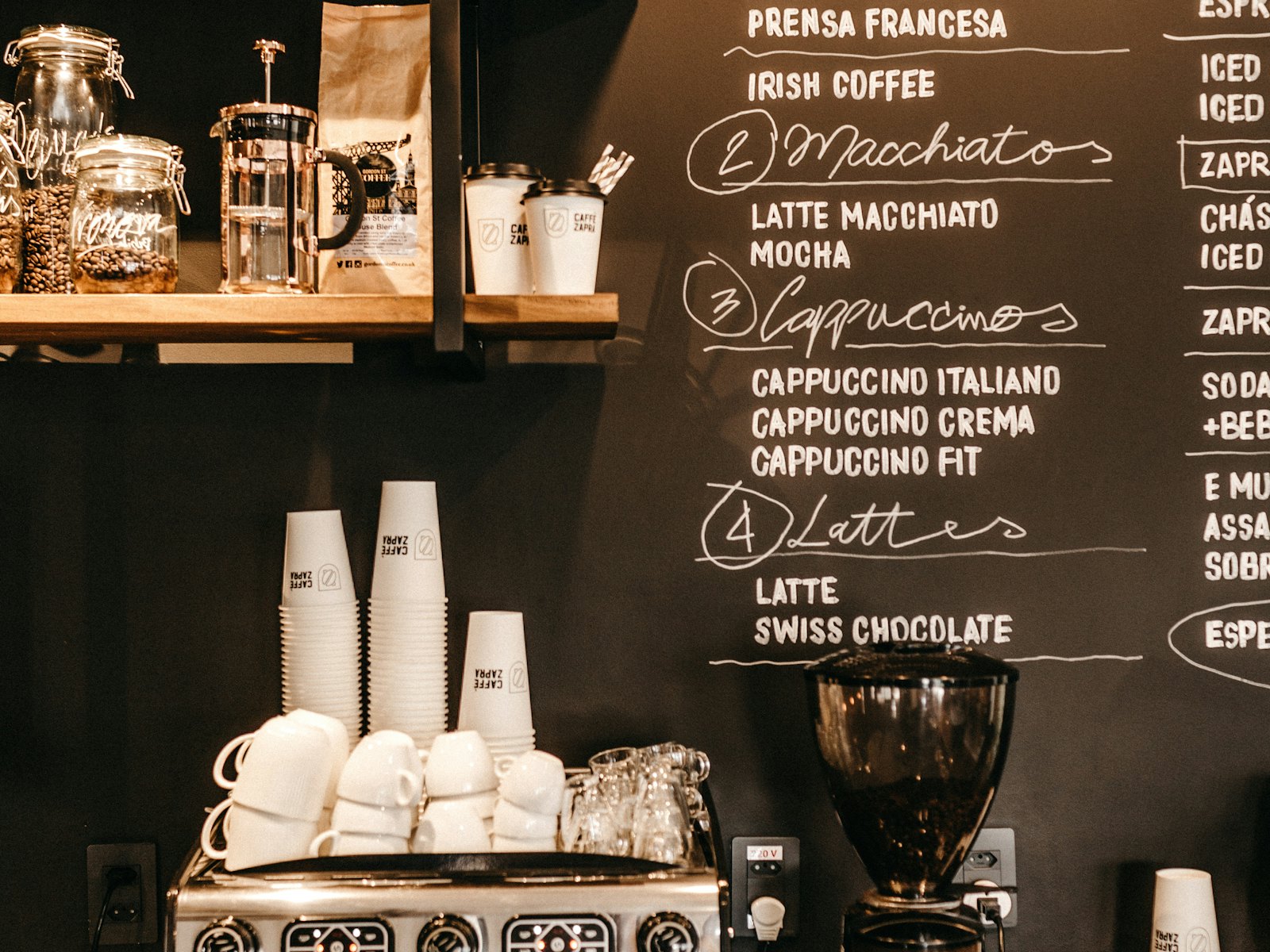 Cups stacked beside the chalkboard menu of coffees and teas