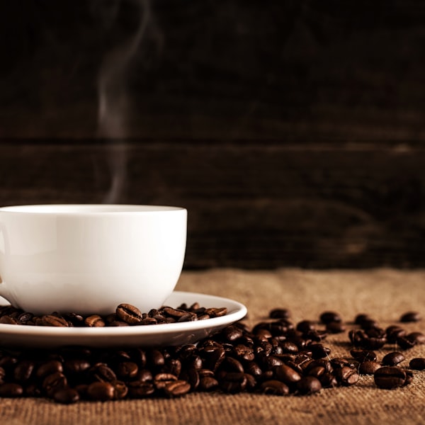 A cup and saucer surrounded by scattered coffee beans