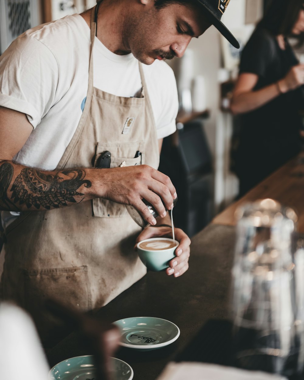 The head roaster in a canvas apron finishing a cup at the bar