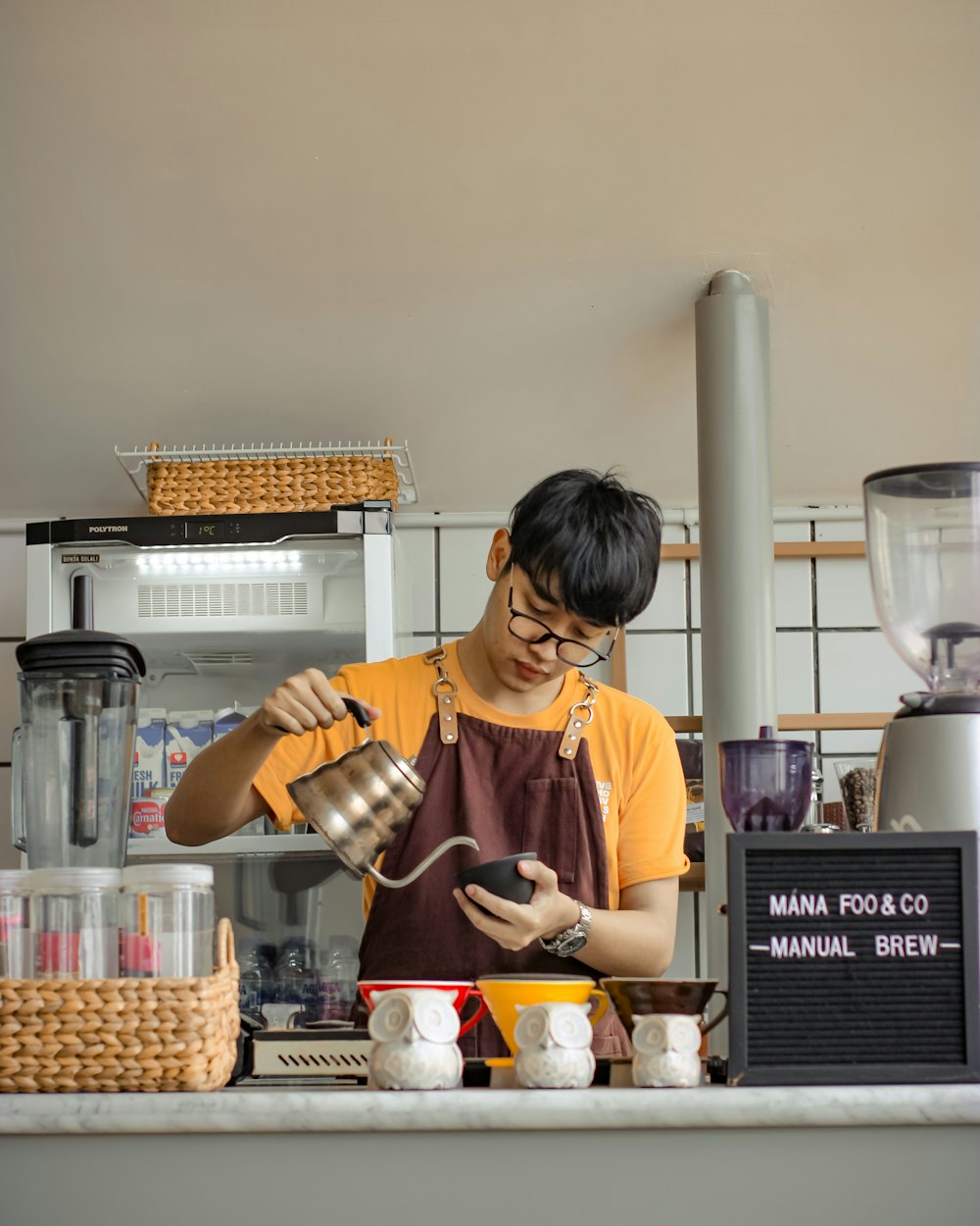 The head barista in an apron working the espresso bar