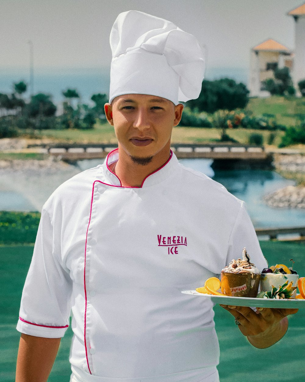 The pastry chef in whites plating a finished dessert