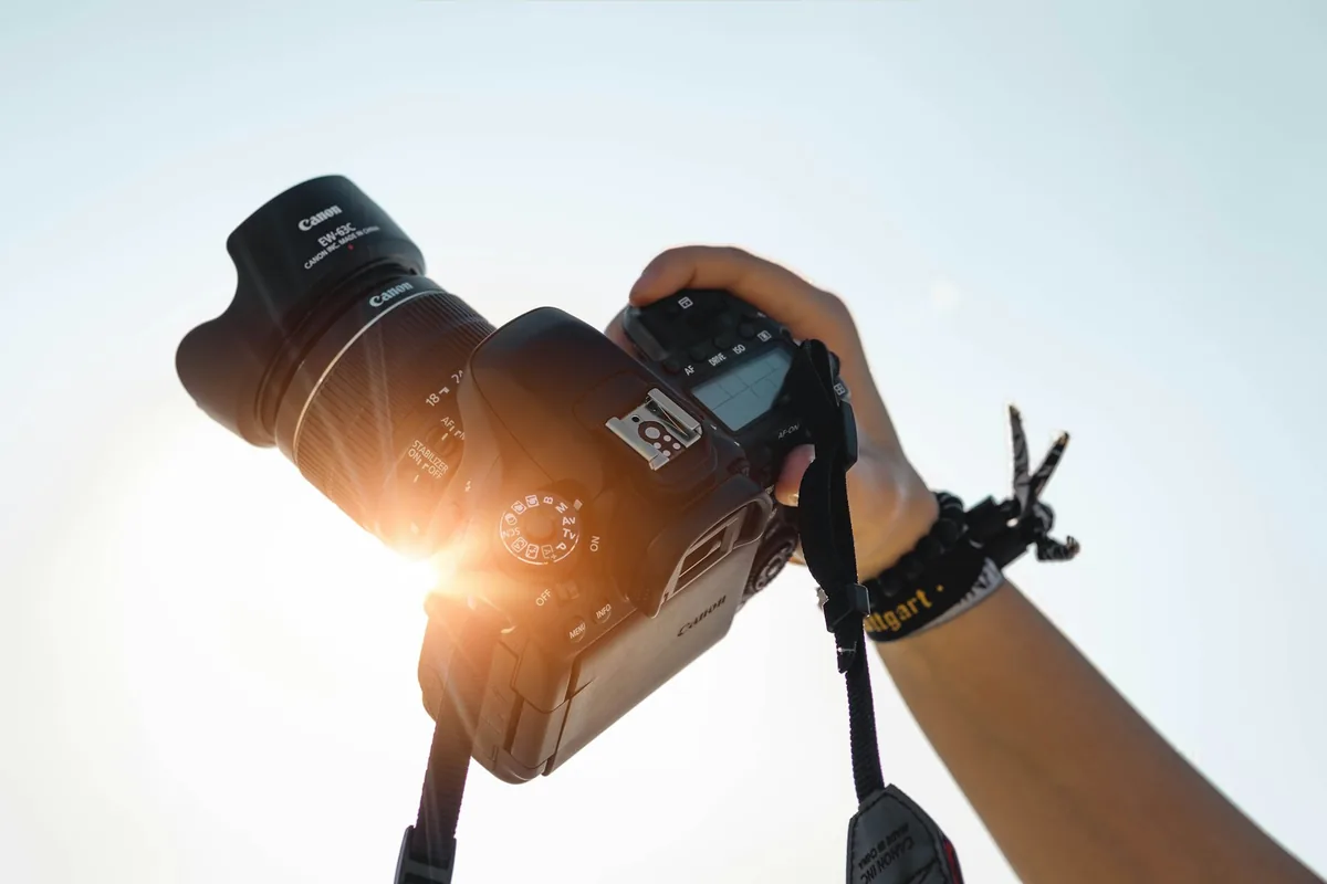 Photographer lifting a camera into backlit sun
