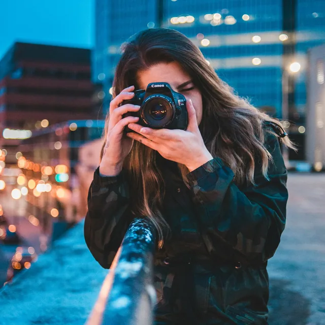 Photographer framing a shot on a city bridge at dusk