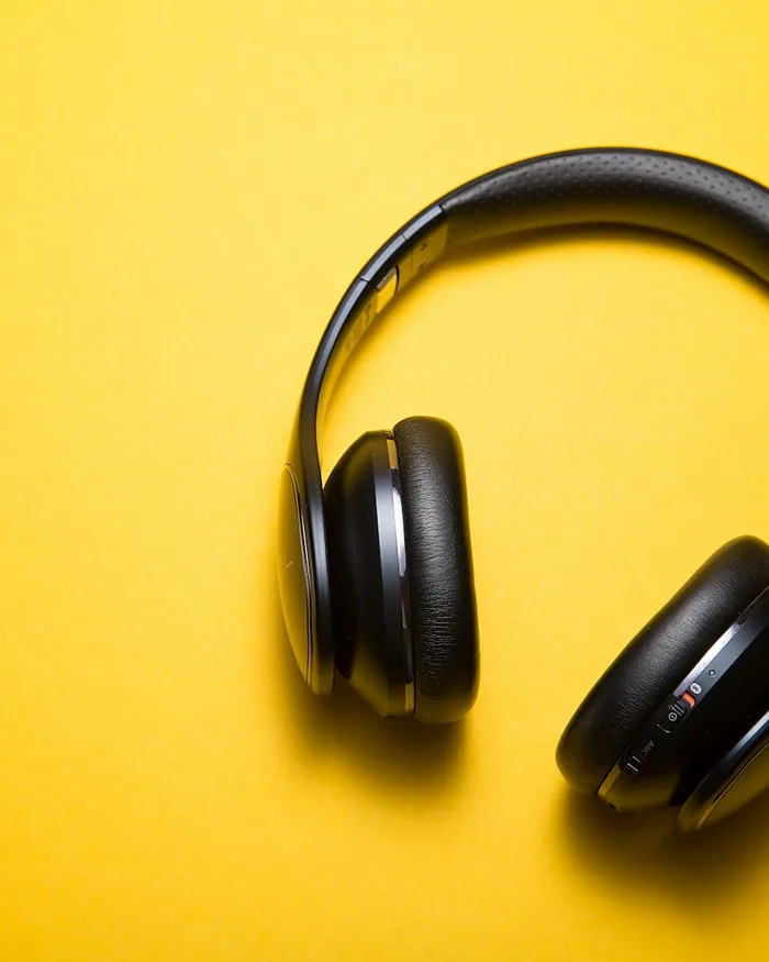 Black over-ear headphones floating on a yellow background