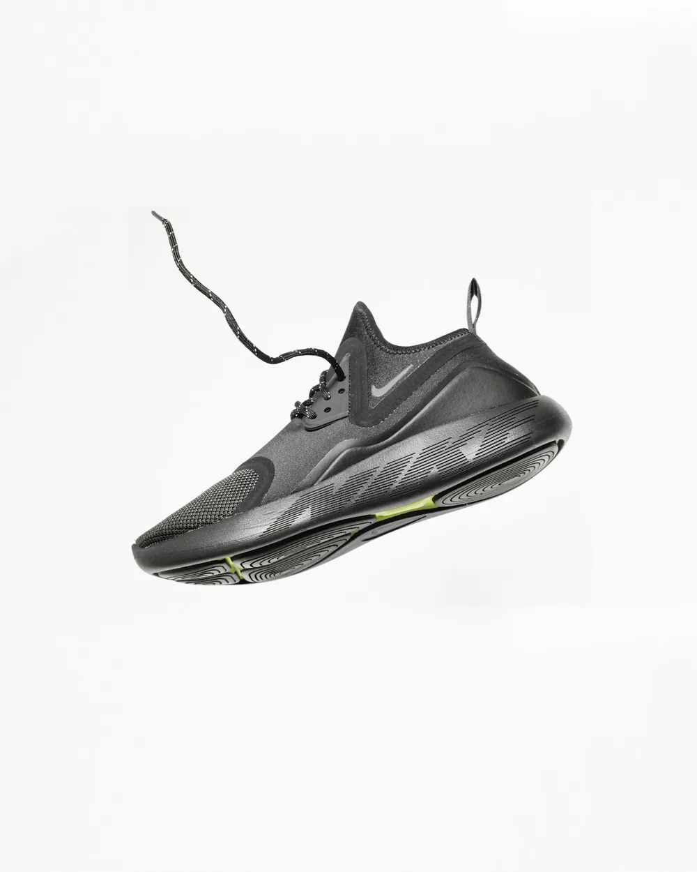 Black running shoe suspended mid-air on white