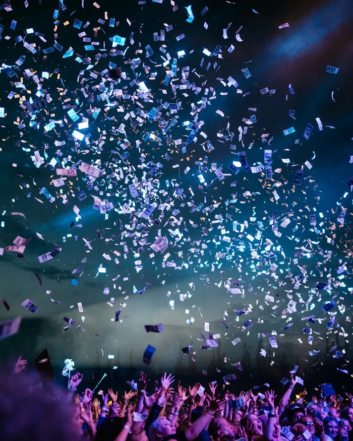 Confetti bursting over a crowd under stage lights