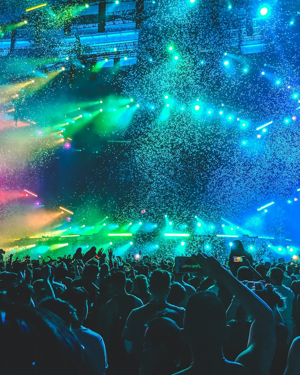 Crowd bathed in blue and green light at a festival mainstage