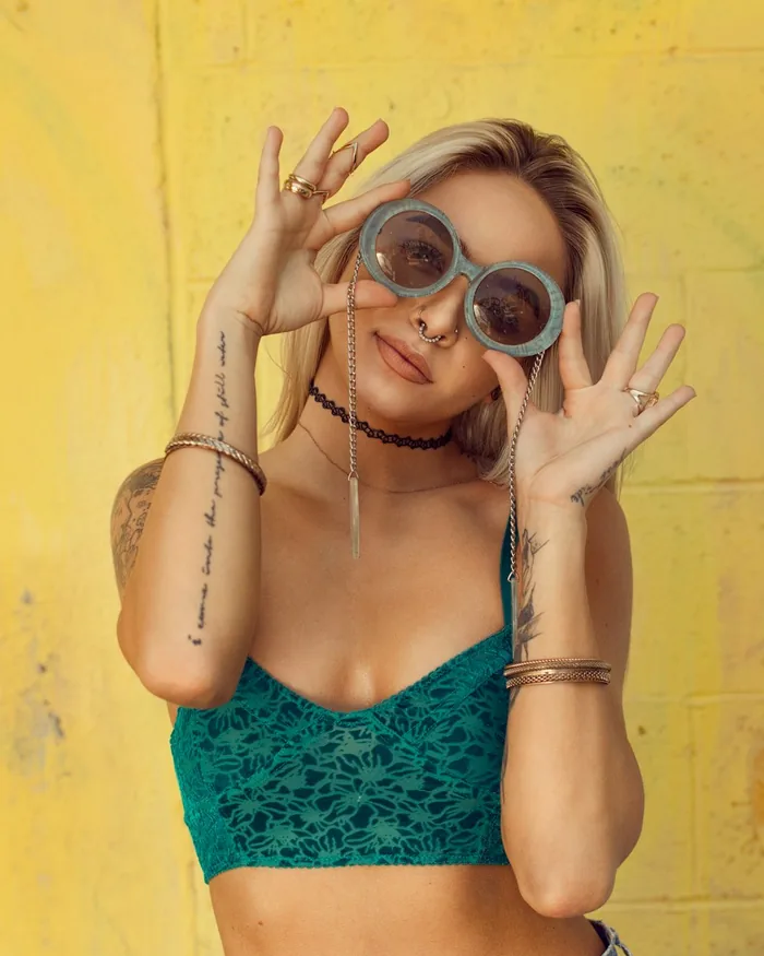 Model in sunglasses against a saturated yellow wall