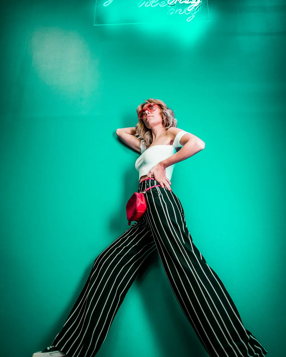 Model posing under a green neon sign in a studio set