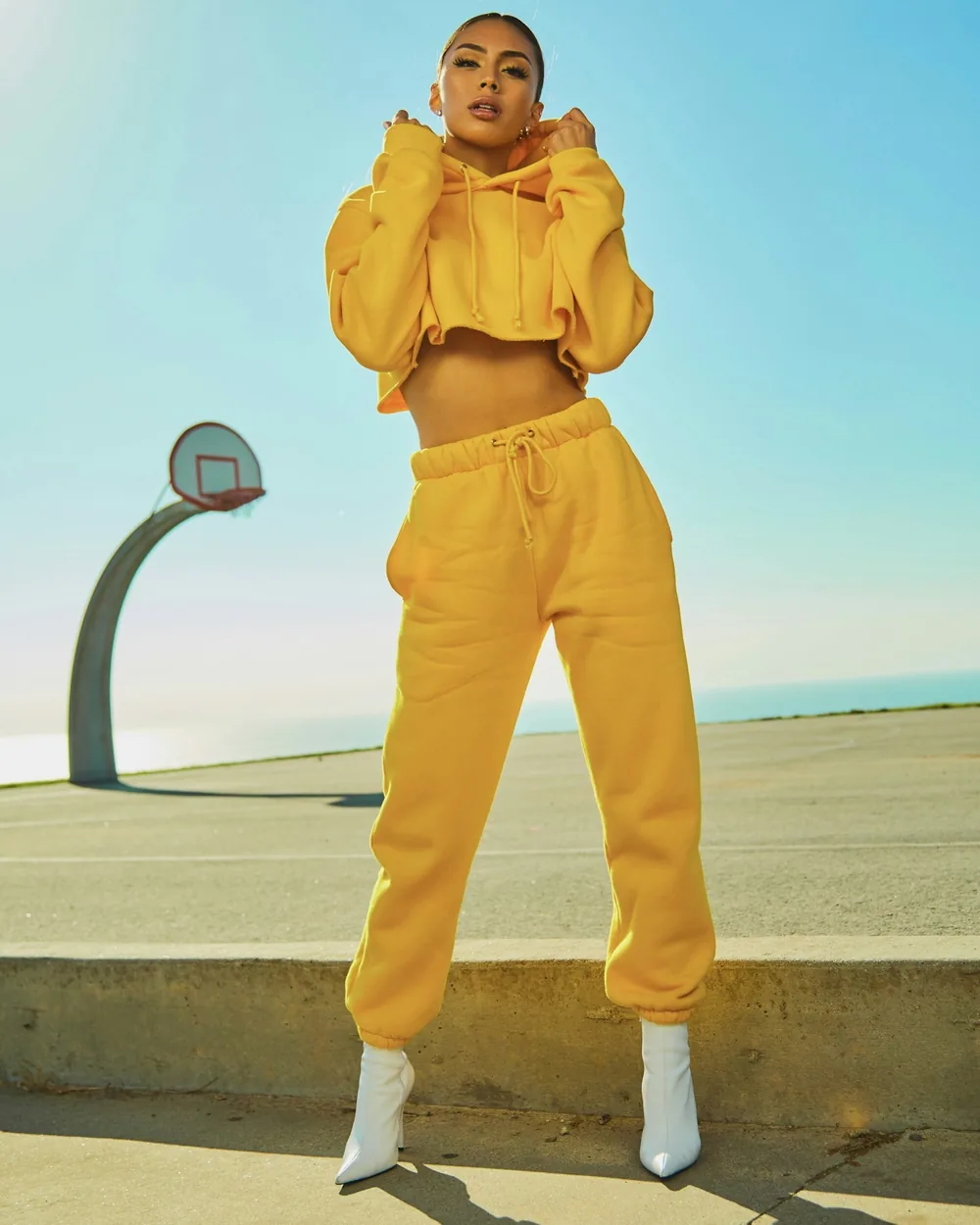 Model in a yellow tracksuit on a sunlit basketball court