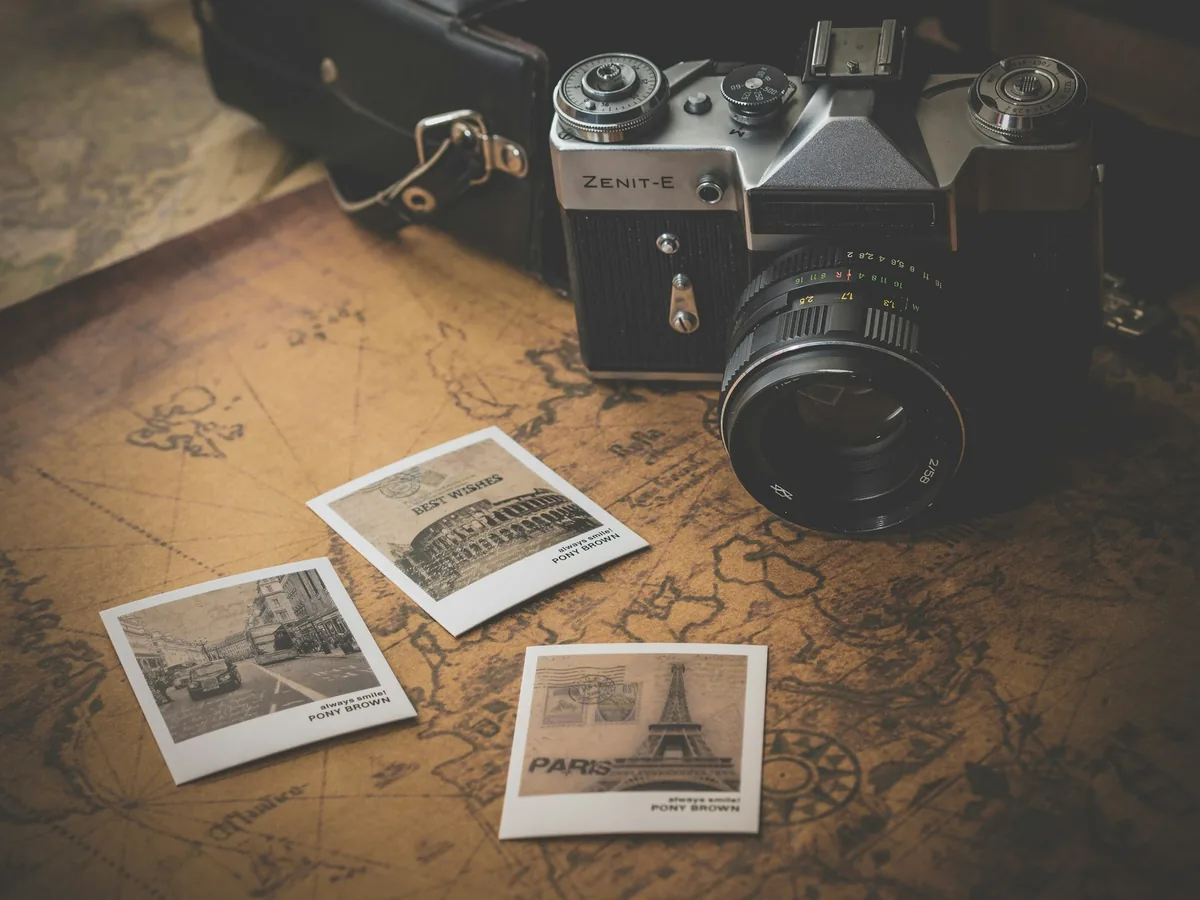 Vintage camera resting beside instant prints and a map