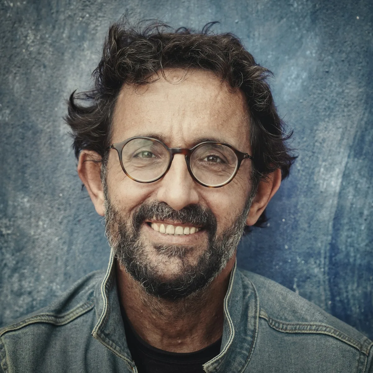 Character portrait of a man with glasses against slate blue