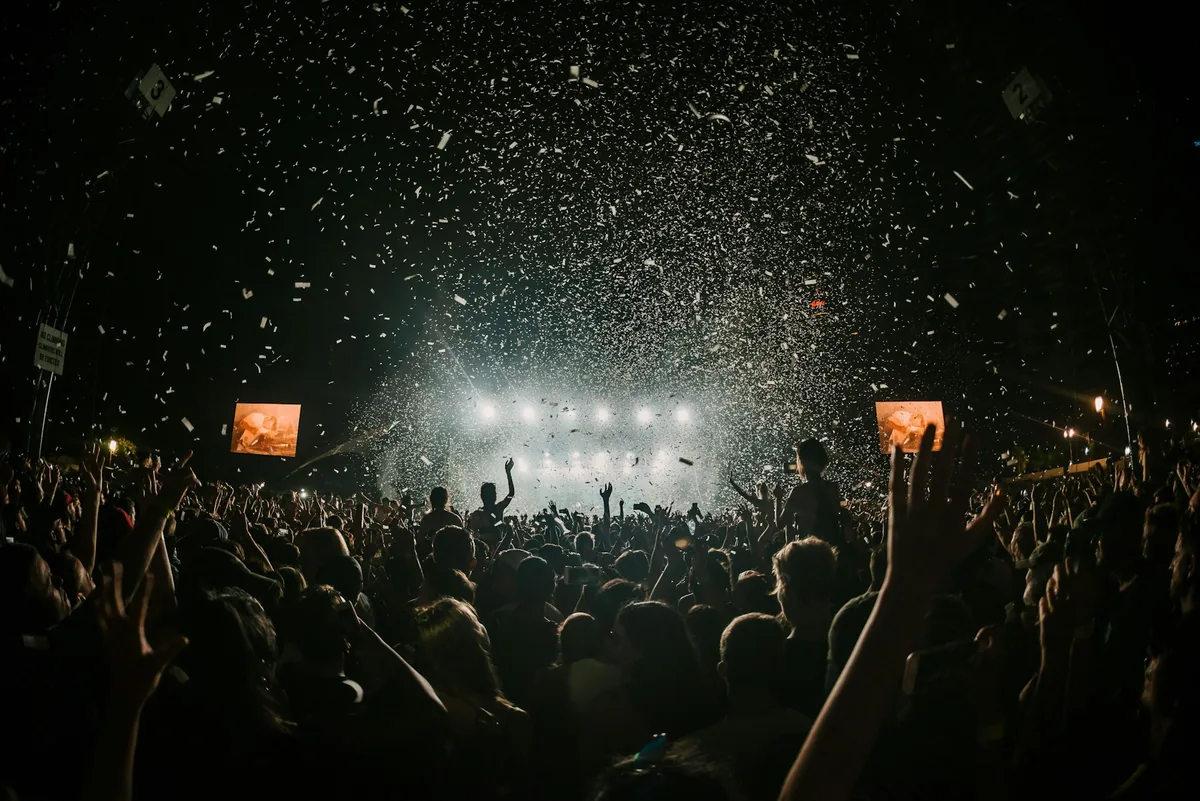 Confetti raining over a crowd with hands in the air