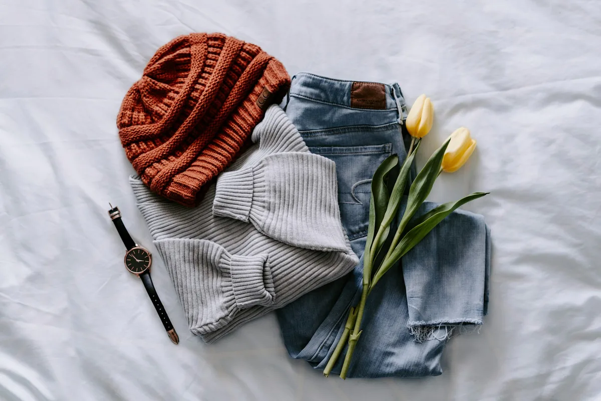 Flat lay of knitwear, denim and tulips on linen