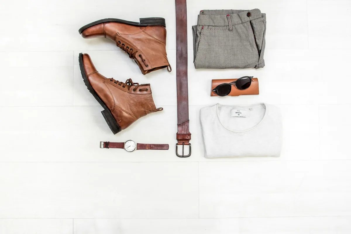 Menswear flat lay with boots, belt and watch