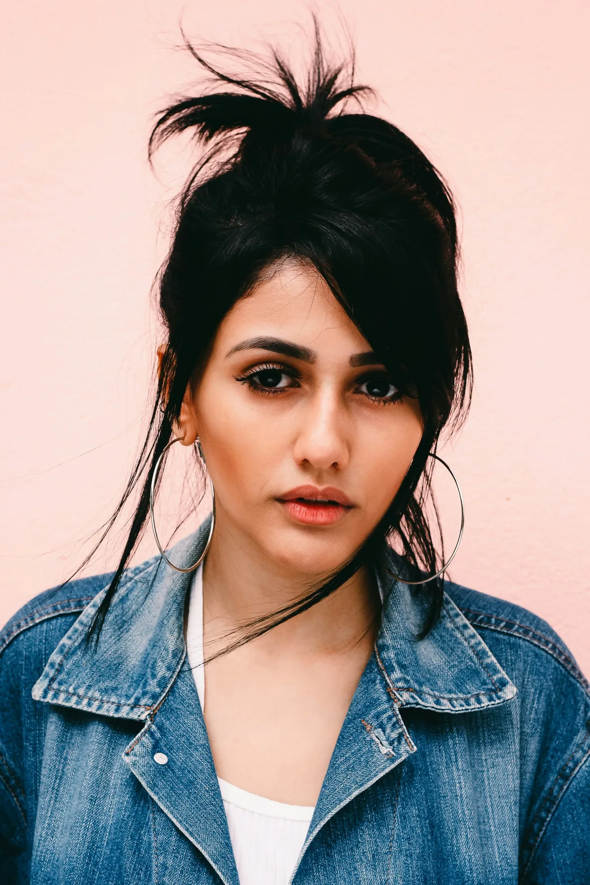 Portrait of a woman in a denim jacket on a pink backdrop