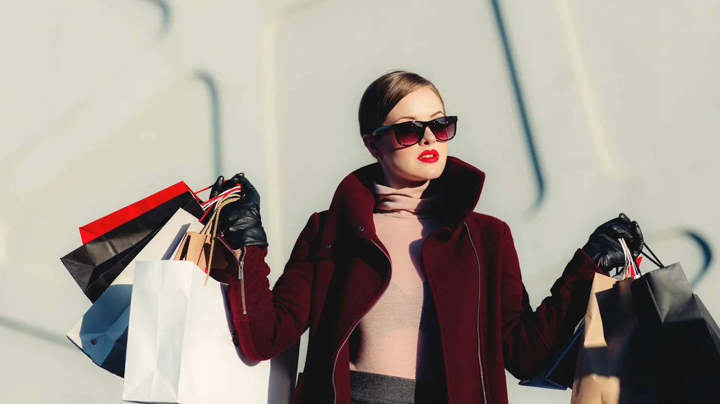 Fashion editorial: model in a burgundy coat with shopping bags