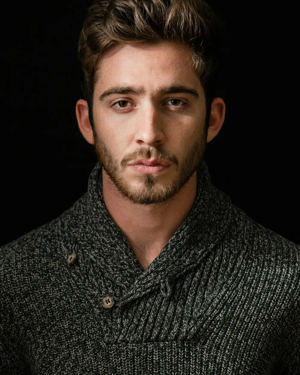 Low-key studio portrait of a man against a black backdrop