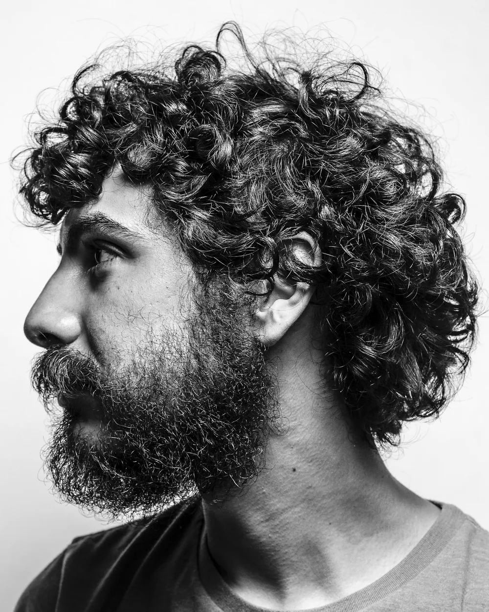 Black and white profile portrait of a man with curly hair