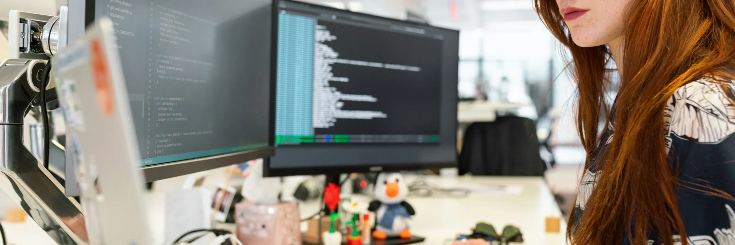 An engineer reading application code across two monitors