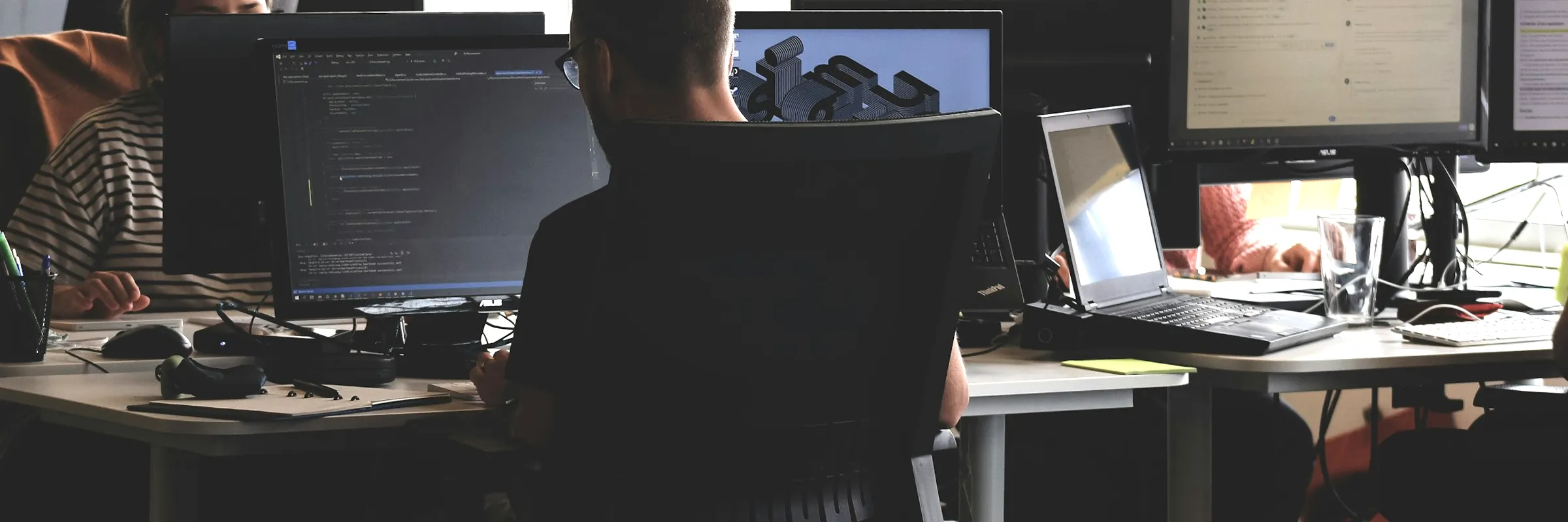 Software engineers working at multi-monitor workstations with source code on screen