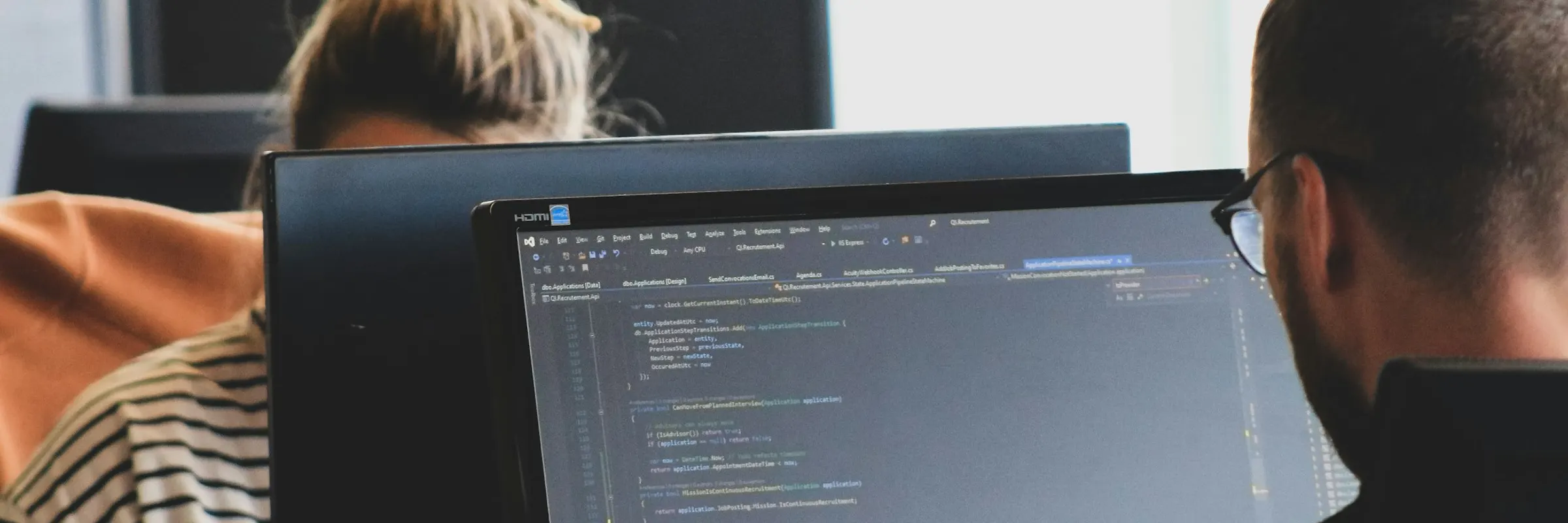Two engineers reviewing source code on a shared monitor