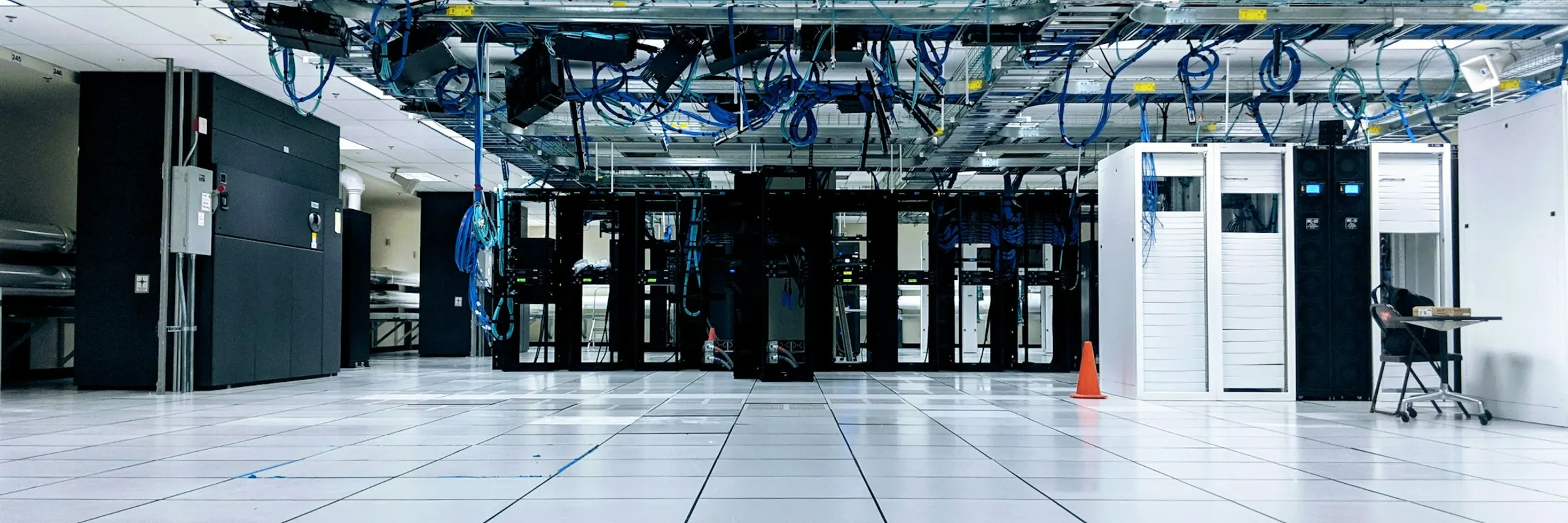 Interior of a data centre, rows of server cabinets and overhead cabling