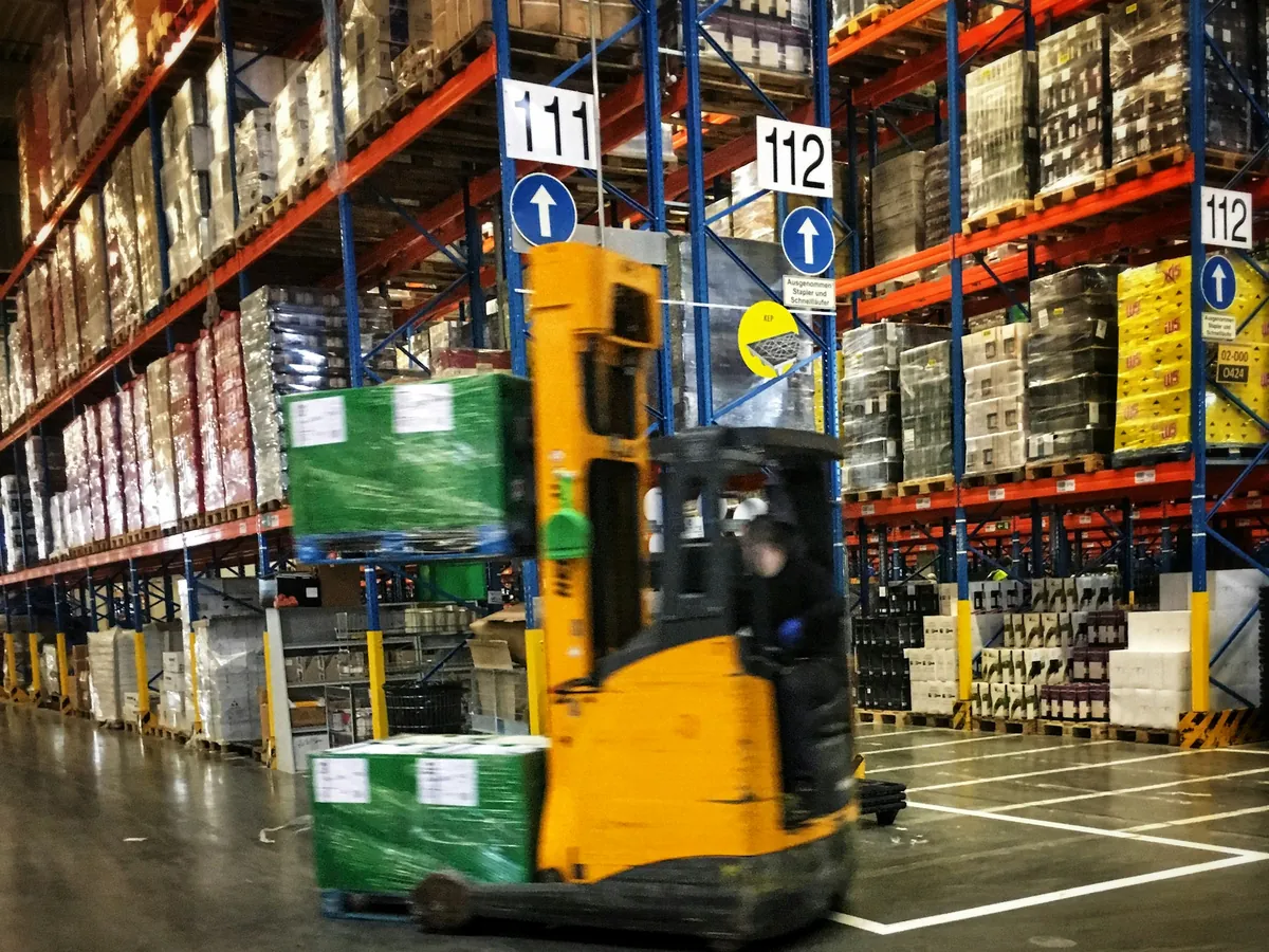 Reach truck moving a pallet through racking aisles at a SwiftRoute warehouse