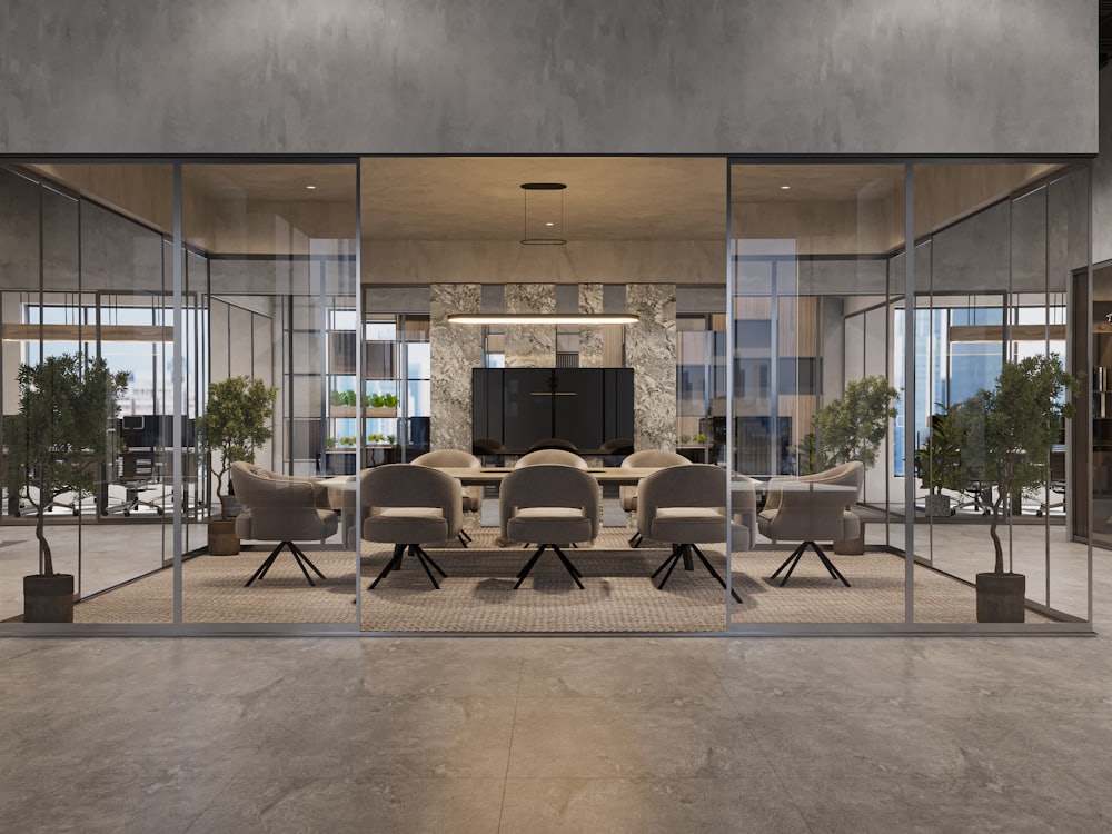 A glass-walled meeting room with a long table and stacking chairs, seen from the office floor