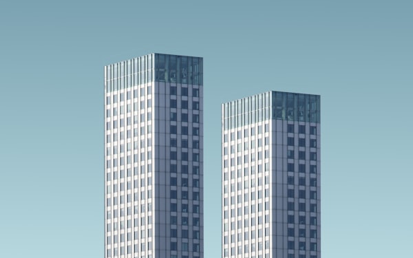 Two teal-and-white glass office towers seen from street level