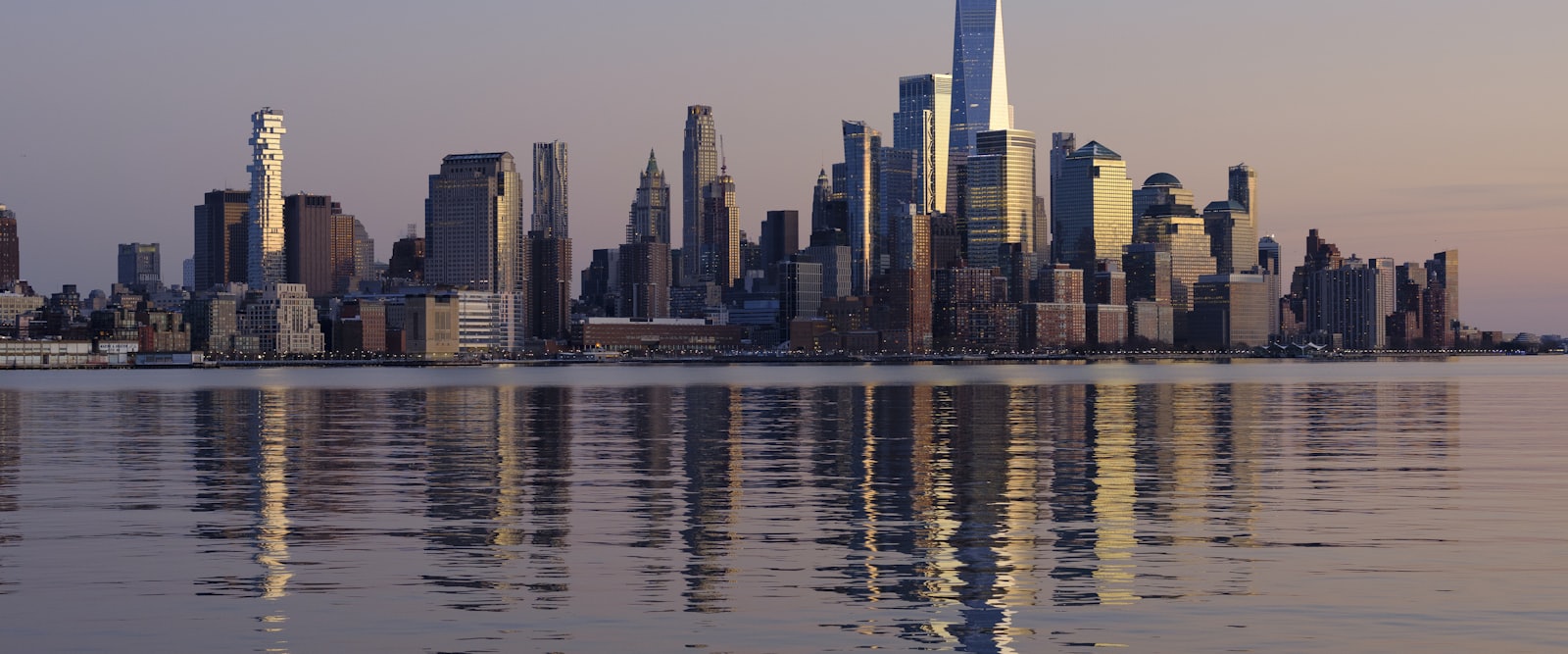 A dense city skyline seen across open water in clear daylight