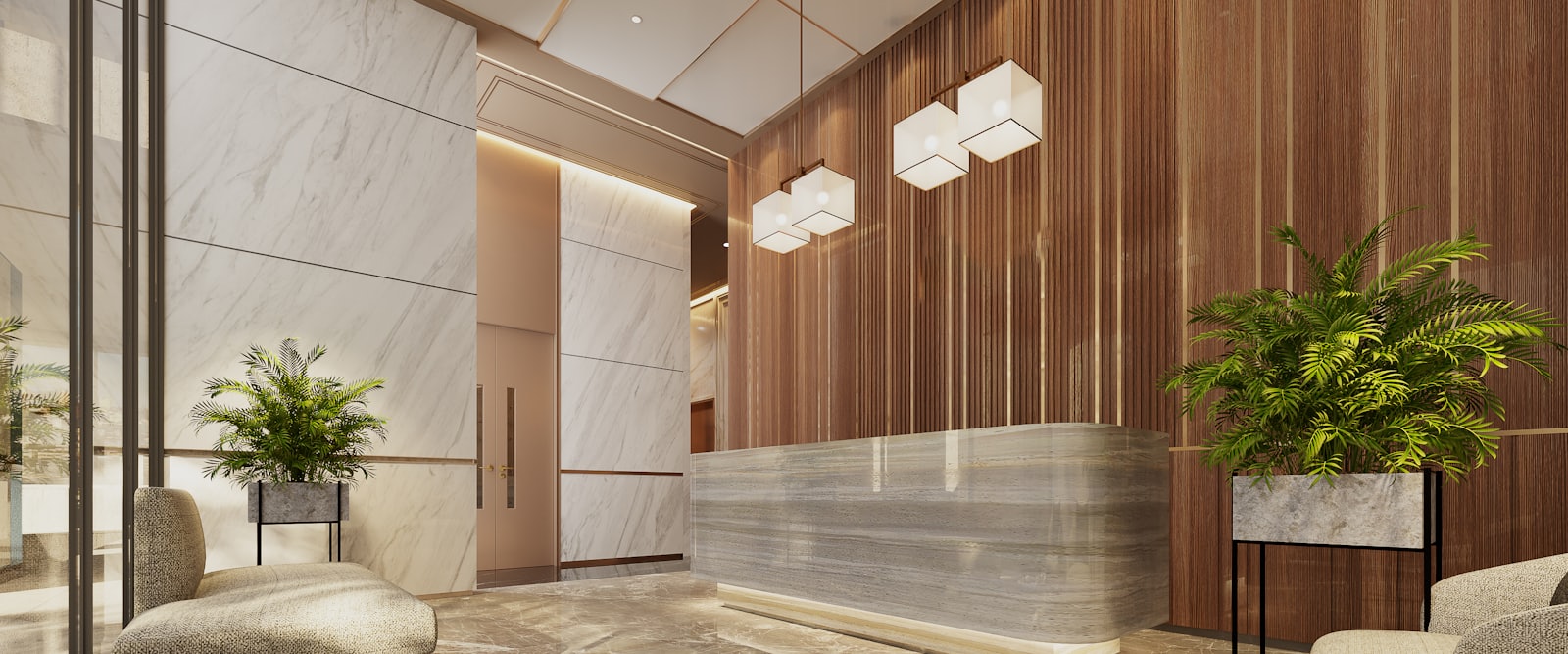 A bright reception lobby with a marble front desk, pale stone floor and potted plants