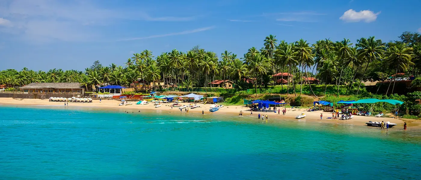 Wide beach with palms and fishing boats in Goa