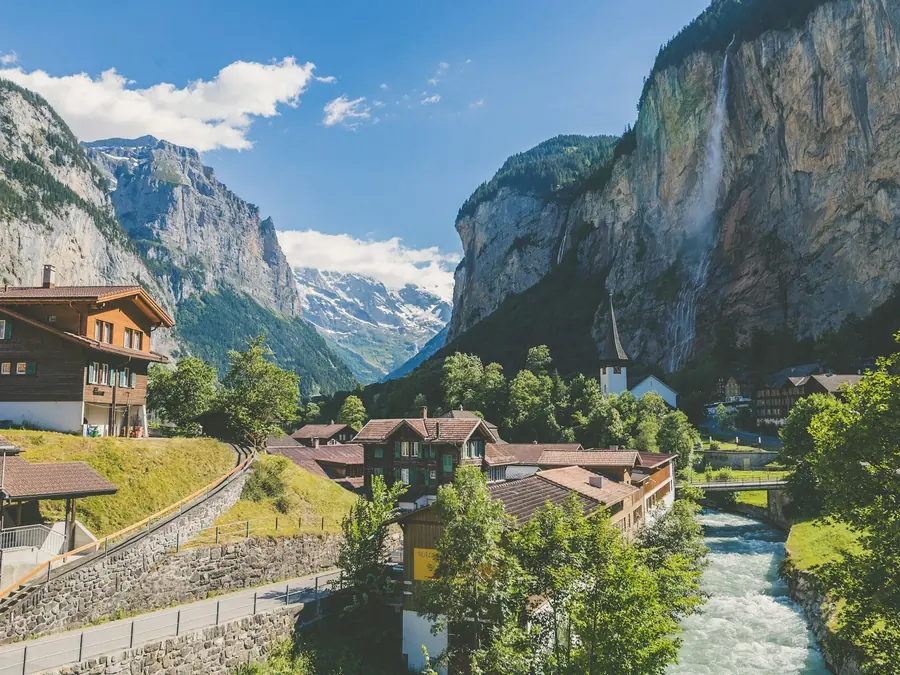 Swiss chalets in a green alpine valley below cliffs