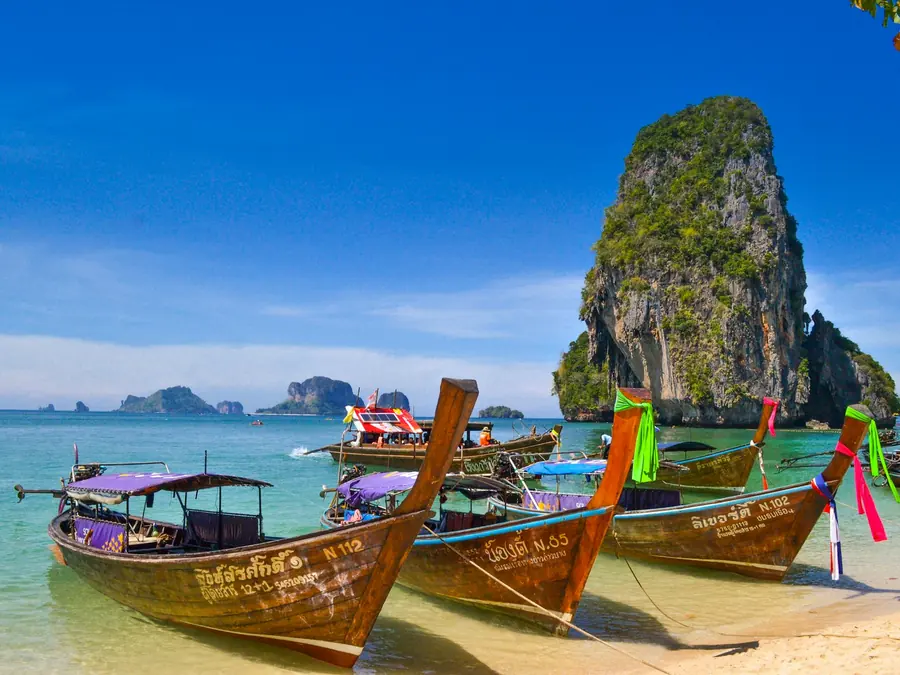 Longtail boats moored beneath limestone cliffs in Thailand