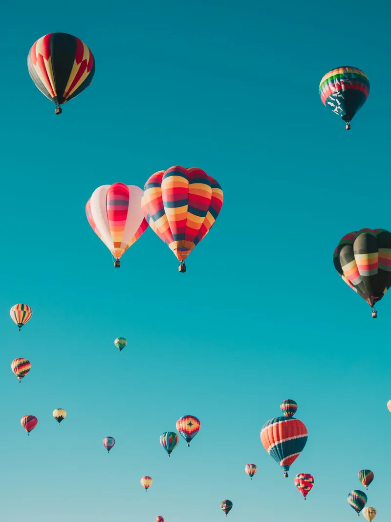 Hot air balloons rising into a clear morning sky