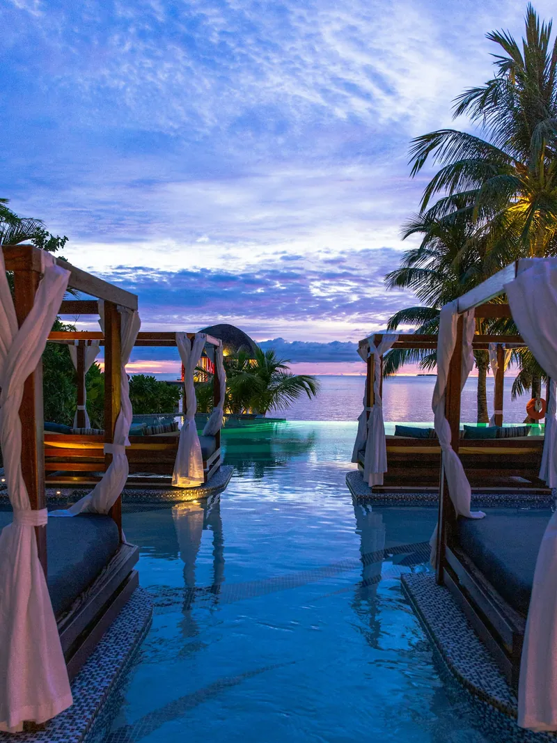 Couple's cabana beside an infinity pool at sunset
