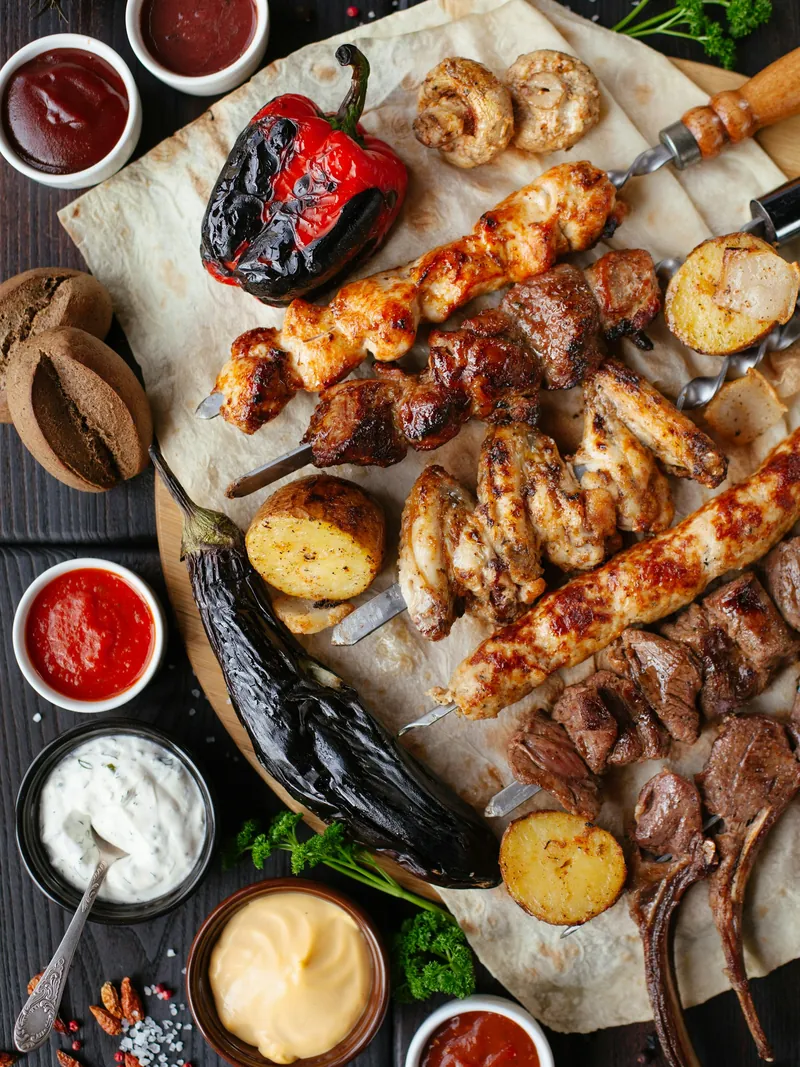 Platter of grilled meats, breads and dips shared at a table