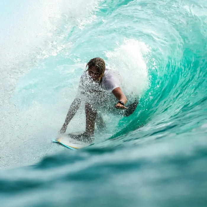 Surfer riding the barrel of a turquoise wave
