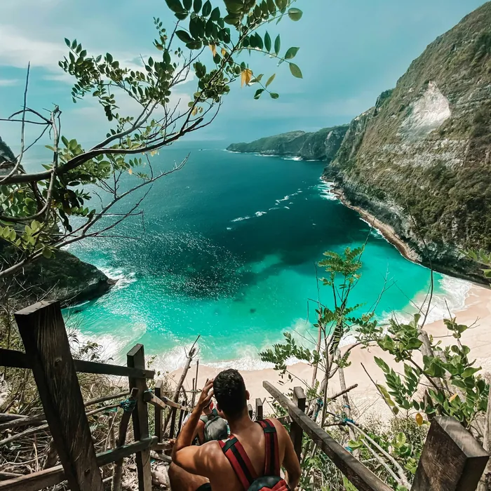 Traveller descending steps toward a tropical bay