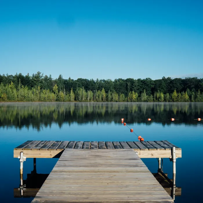Wooden jetty reaching into a still forest lake