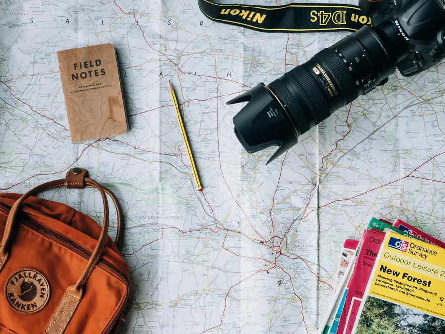 Camera, map and travel notebook laid out on a desk