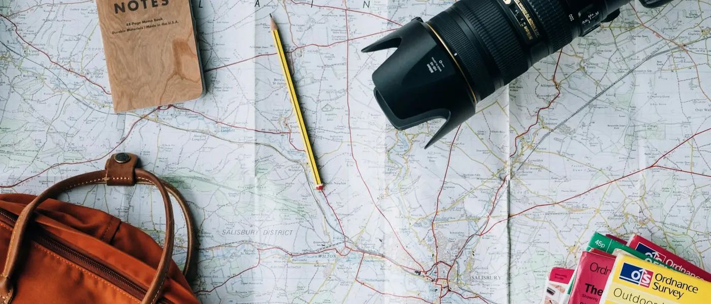 Travel flat lay with a camera, map, notebook and backpack