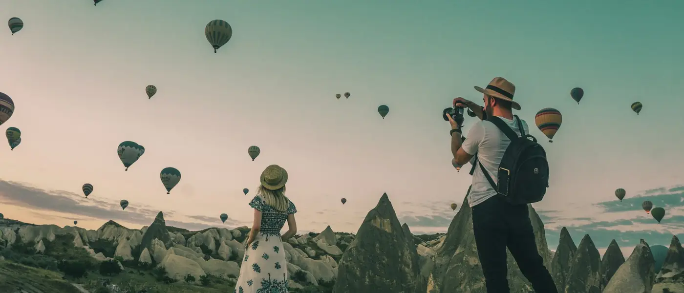 Hot air balloons drifting over a valley at sunrise