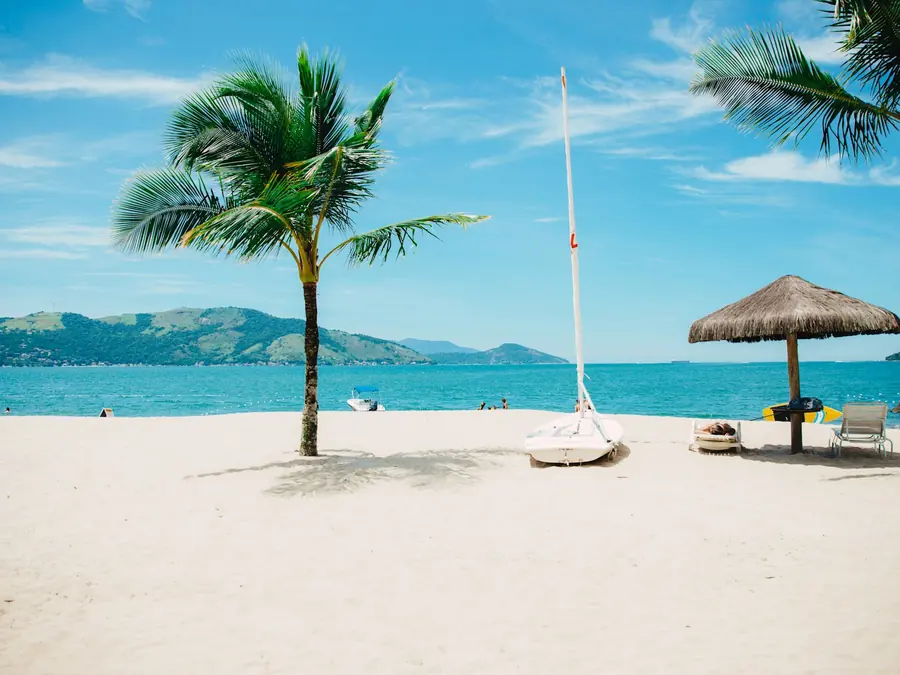 Golden beach with palms and a wooden boat at low tide